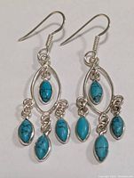 Front view of a pair of silver turquoise dangle earrings showing the marquise-shaped turquoise stones and silver oval frames.