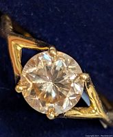 Close-up image of silver ring with round cut yellow moissanite gemstone and yellow gold triangular accents on band.