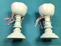 Pair of teal glass lustres on teal fabric background showing full side view with hanging glass prisms