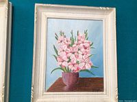Oil painting of bright pink flowers in a brown vase with green stems and leaves, framed in white.