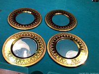 Overhead photo showing all four cranberry glass chargers with gold decorative rims.