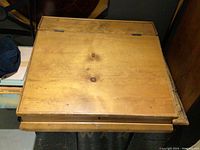 Closed pine countertop desk showing the hinged lid and knob, rectangular with wood grain visible.