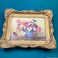 Front view of the signed floral oil painting in a decorative gold-tone ornate frame showing colorful flower bouquet.