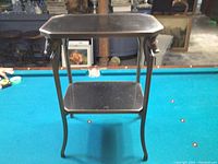Front view of two-tier table with granite top and shelf on pool table background