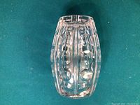 Clear lead crystal vase shown upright on a green felt surface, highlighting its transparency and cut decorative patterns from side view.