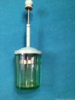 Glass container with metal plunger top showing uranium green color, minor wear on metal parts.