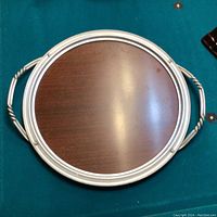 Top view of an oval serving tray with a brushed aluminum metal frame and mahogany Formica surface, showing two twisted metal handles and raised edge detailing.