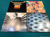 Four vinyl LP records arranged on a green surface showing cover artwork from The Animals, The Who, and Pete Townshend albums.