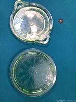 Two uranium glass cake plates shown on turquoise cloth, front view under normal light.