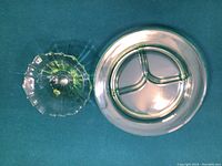 Top-down photo of clear glass sectional plate with three compartments and smaller candy dish on teal fabric background.