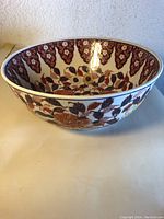 Side view of the antique Imari porcelain bowl showing detailed floral leaf pattern and scalloped rim design.