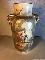 Front view of the porcelain vase showing painted scene of couple and gold handles