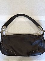 Front view of the black leather purse with white stitching and single strap.