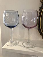 Two Waterford Crystal Marquis Polka Dot all-purpose wine glasses side by side; one blue and one rose color.