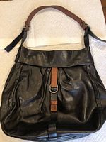 Front view of black leather Joanel handbag showing front flap and buckle detail.