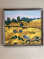 Full view of oil painting in silver metal frame showing landscape of yellow fields and green trees under blue sky