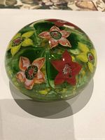Top view showing red, orange, and yellow flower inclusions within the green glass base of the paperweight.