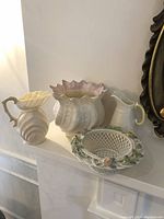 Four Belleek porcelain vases and a basket dish displayed on a mantle