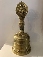 Front view of the Tibetan bronze Vajra bell showing the engraved floral design on the bell and detailed vajra handle.
