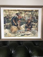 Full view of Vietnamese watercolor painting showing multiple people and baskets at a market, framed and mounted on wall.
