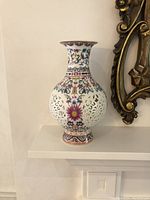 Full view of the vase on a shelf showing entire form and floral pierced design.
