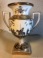 Front view of vintage porcelain vase showing black and gold horse and rider design with floral and gold accents.