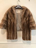 Full front view of the vintage brown Lunaraine mink stole hanging on a hanger showing its length and shape.