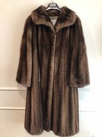 Front view of full-length brown mink fur coat hanging on a branded hanger