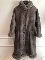 Full-length front view of brown sheepskin coat hanging with fur collar, cuffs, and hem, button closure, angled pockets visible.
