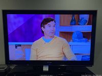 Sharp 52-inch Liquid Crystal TV powered on showing video content.