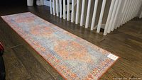 Full view of the oriental style carpet runner laid out on a wooden floor, showing overall color and pattern.