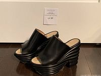 Three-quarter front view of pair on wood floor with auction tag