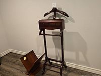 Full view of gentleman's butler next to bent plywood magazine holder on floor.