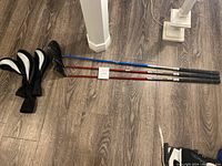 Full view of the three Wilson Staff drivers lying on wooden floor along with their club covers