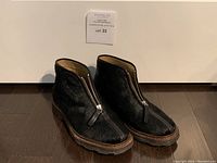 Pair of womens Lemaire black pony hair zippered boots photographed from front angle showing zipper and shape.