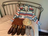 Colorful Zara jacket, brown faux leather joggers, straw hat, Todds suede loafers, Cole Haan leather loafers and wool slippers displayed on bed and hanger.