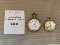 Two antique pocket watches side by side, gold plated Bulova and D. Blake Walton Ontario, with a lot card