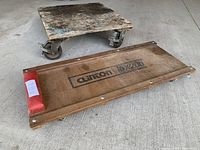 Two wooden dollies: a square furniture dolly with wheels and a rectangular car dolly with the brand 'Clinton DXY11' and a red padded headrest