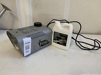 Full view of fog machine and fluid container on white surface