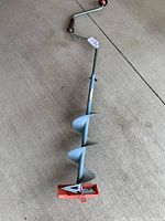 Full length view of the manual ice auger on concrete floor showing spiral blade and base blades