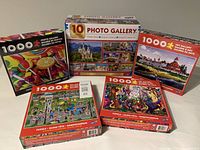 Photo showing five boxed jigsaw puzzles in the lot placed on a surface.