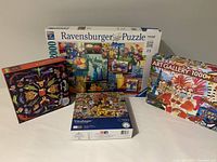 Four 1000-piece jigsaw puzzles displayed side by side: Ravensburger, Educa, Halloween-themed, and Vintage brand.