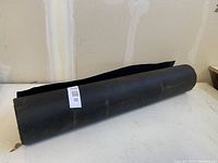 Photo of a single roll of black tar paper on a table against a partially finished wall.