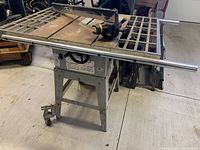 Full view of Bexon table saw with large metal grid table, adjustable fence, and blade guard in a garage setting.
