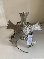 View of the vintage metal light fixture from the top, showing its floral-style central rosette and outward extending decorative arms.