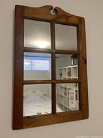 Rectangular wooden framed wall mirror with six individual mirrored panes. The top of the wooden frame features a decorative cutout.