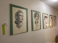 Five pencil portrait sketches in green frames hung on wall, showing full lot display