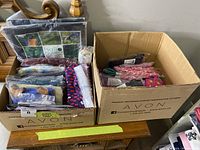 Two boxes filled with Avon bags, socks, and other accessories.