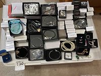 Overview of the Avon jewelry items including bracelets, rings, and charms in boxes and pouches arrayed on a surface.