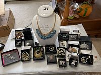 Full view of the display bust with necklace and surrounding boxed Avon jewelry items including bracelets, necklaces, pendants, and a brooch.